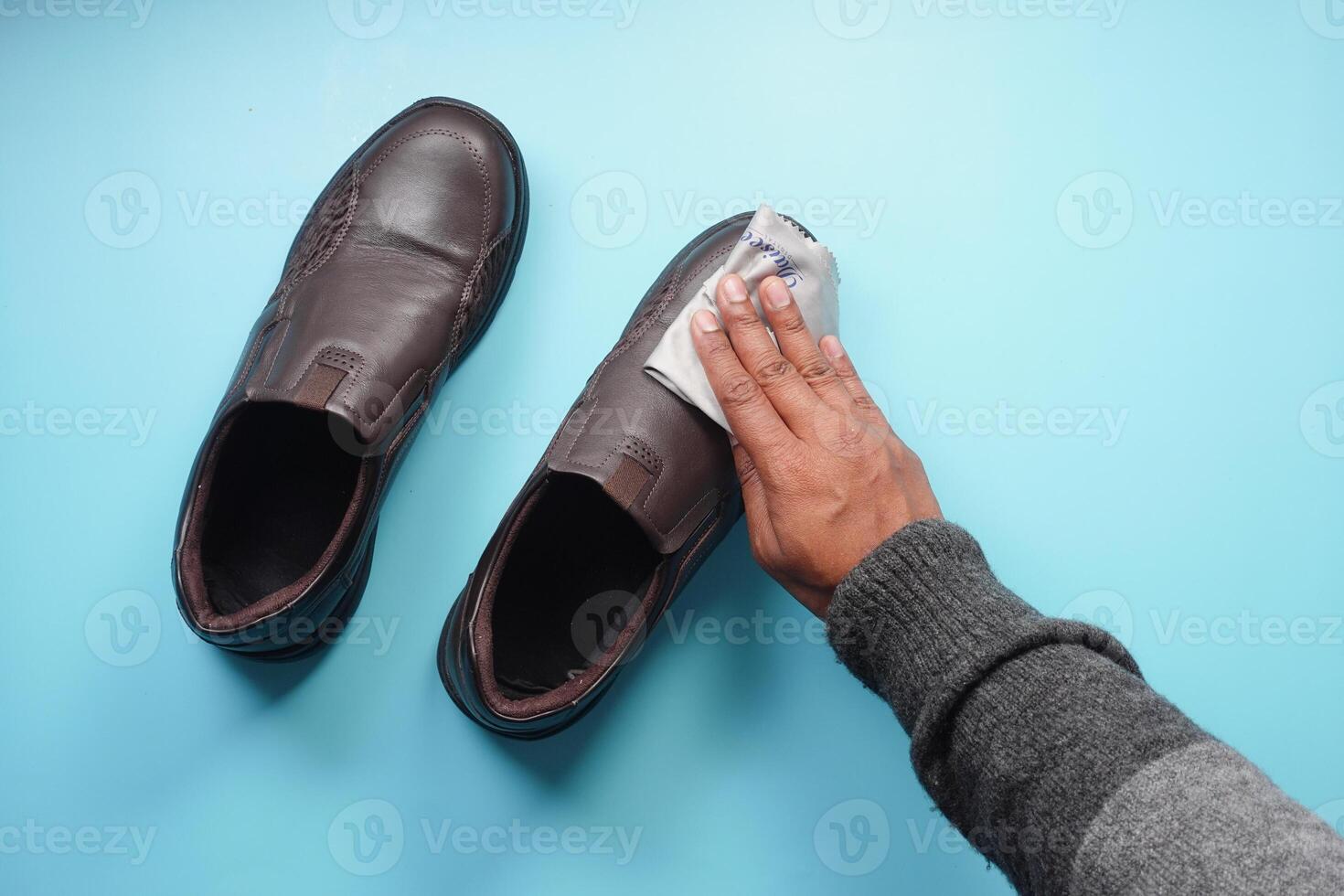 Men wipes his leather shoes with a wet cloth photo