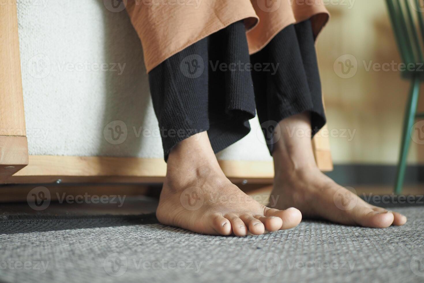 Woman sitting on sofa with feet on carpet at home. photo