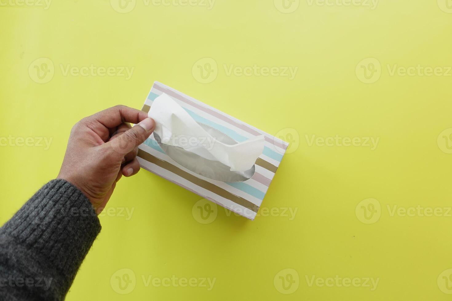 hand pull out a piece of tissue from tissue paper box photo