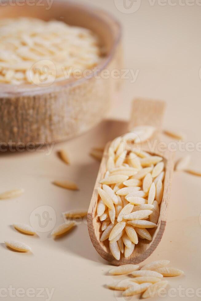brown long rice in a wooden spoon on table . photo