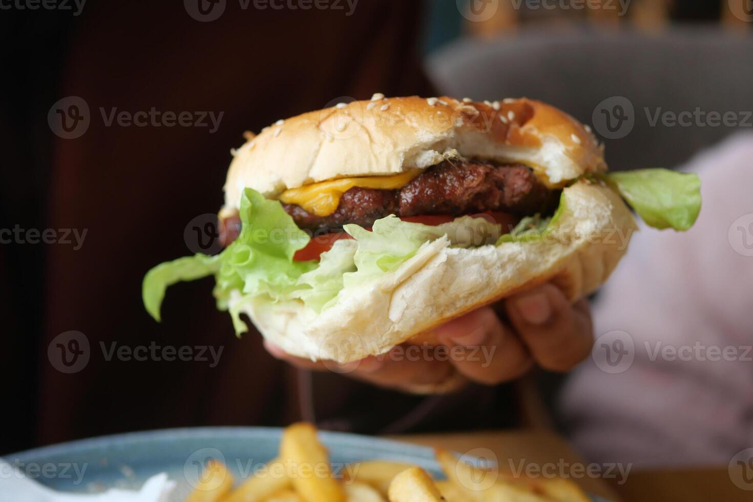 hand holding beef burger on table close up photo