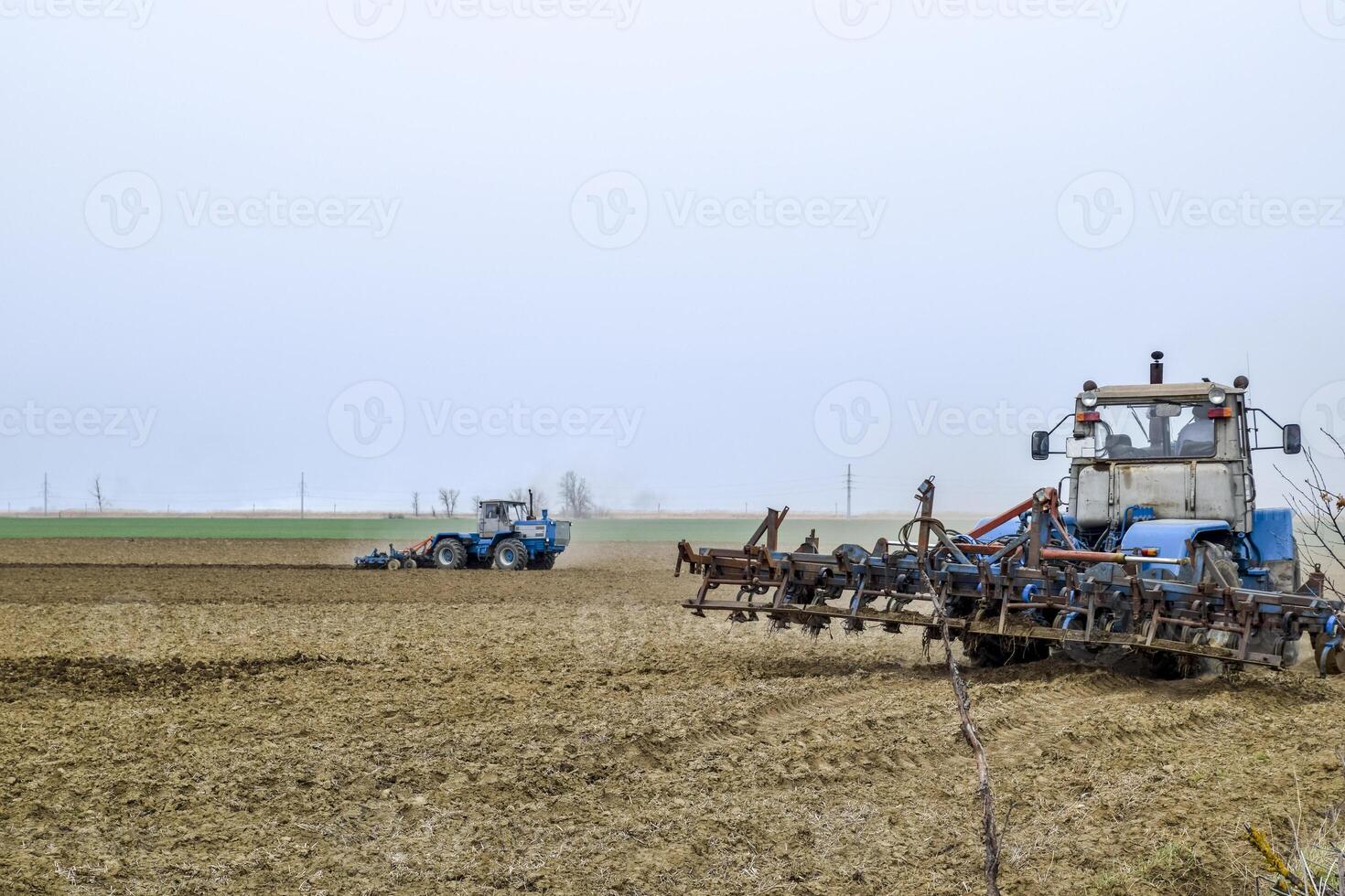 Lush and loosen the soil on the field before sowing. The tractor plows a field with a plow photo