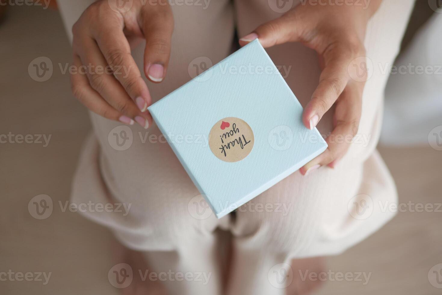 hand putting a thank you sticker on a gift box photo