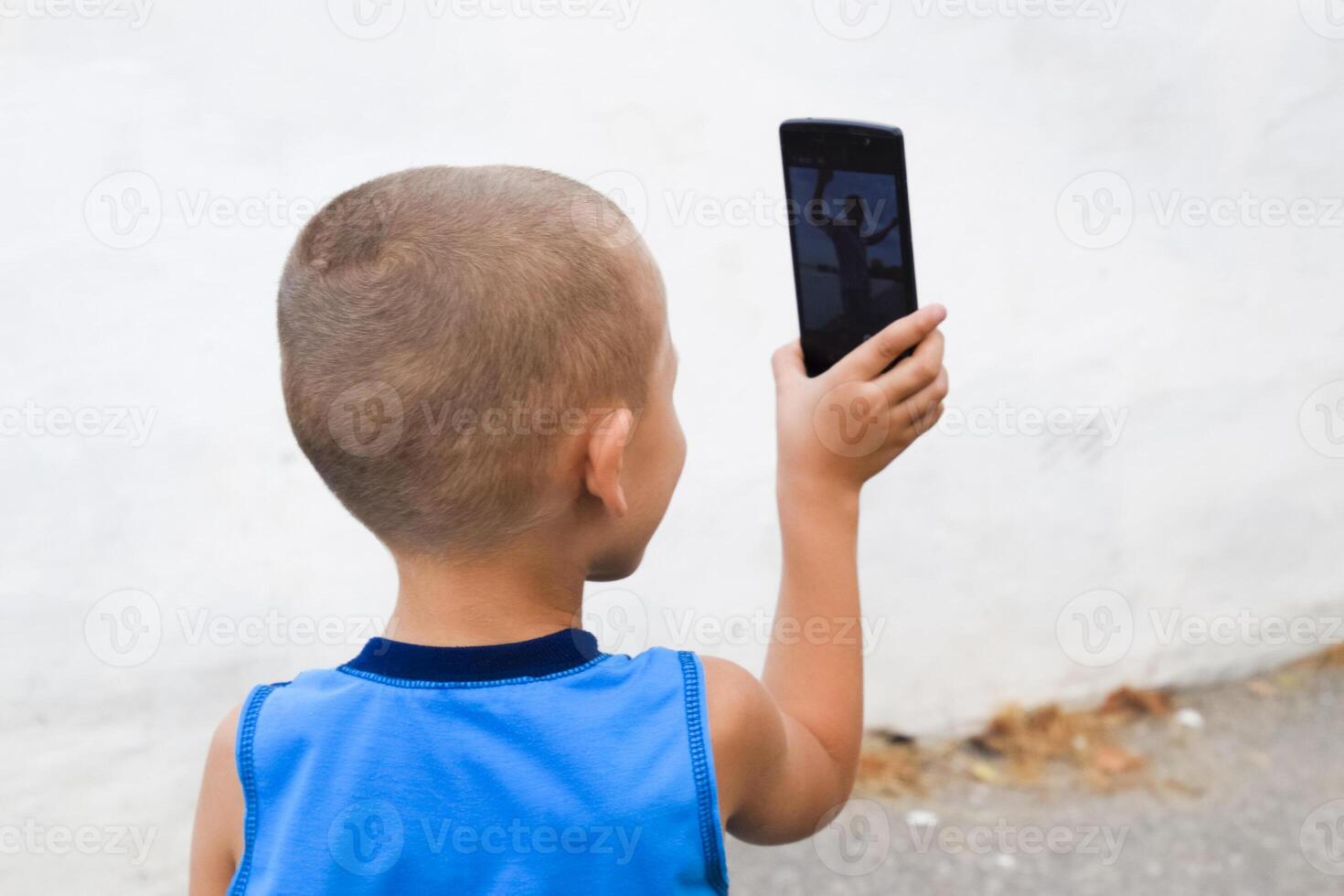 Child with a smartphone. A little boy shoots video on a smartphone. photo