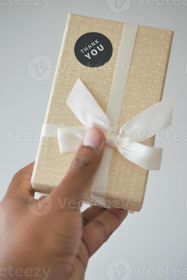 hand putting a thank you sticker on a gift box photo