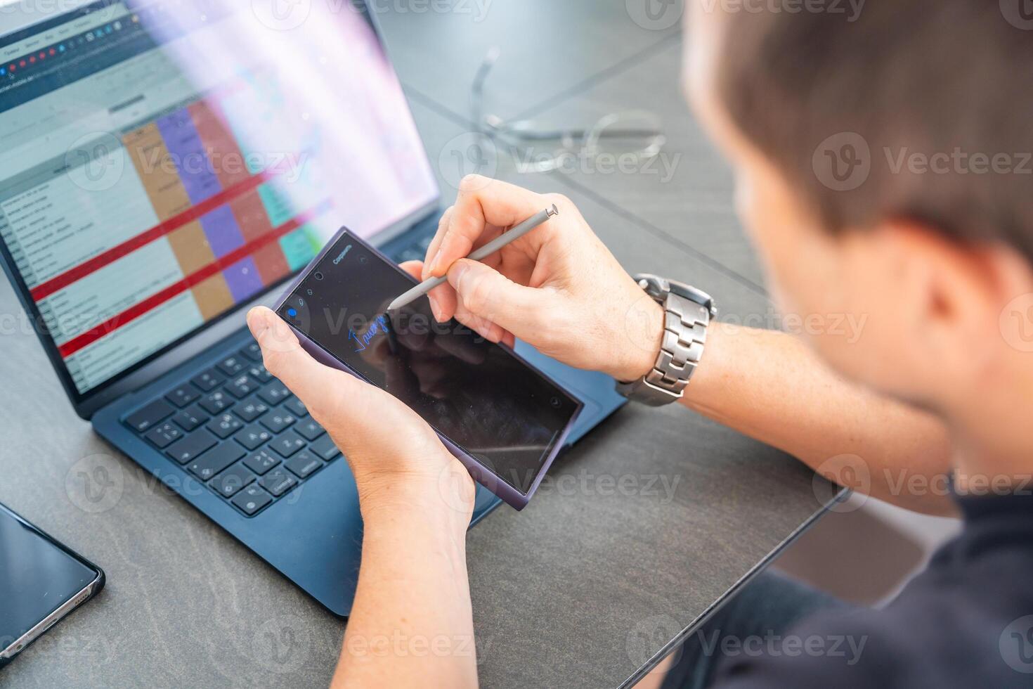 Close up view of man hand holding smart phone and stylus pen at his creative workspace. photo