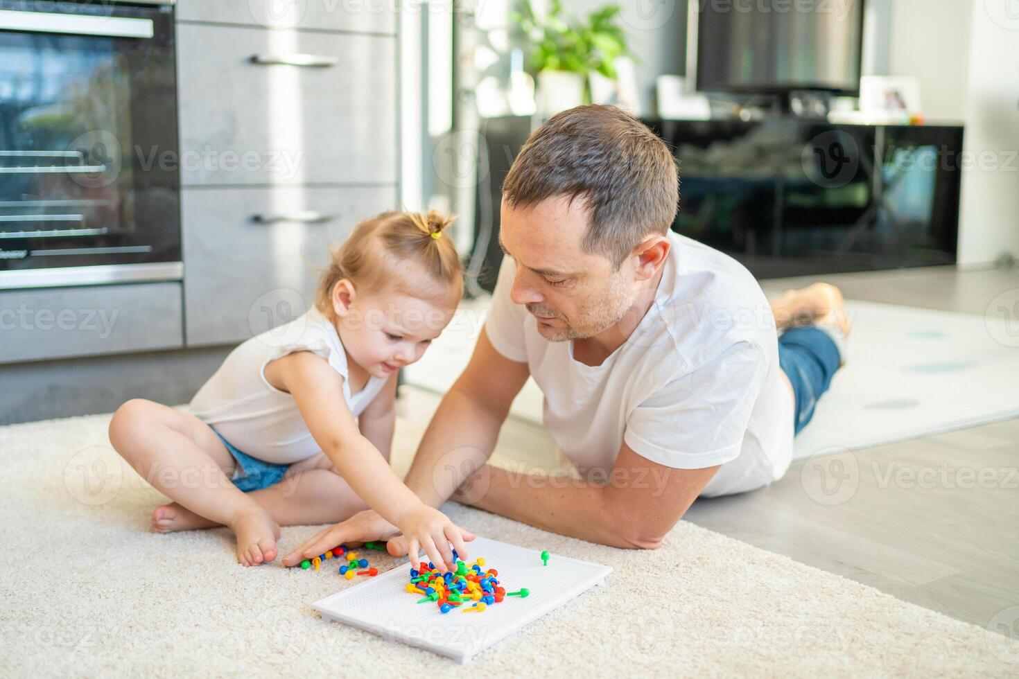Cute little girl playing with mushroom nail mosaic. Father and baby playing together concept. Hobby and leisure time. photo