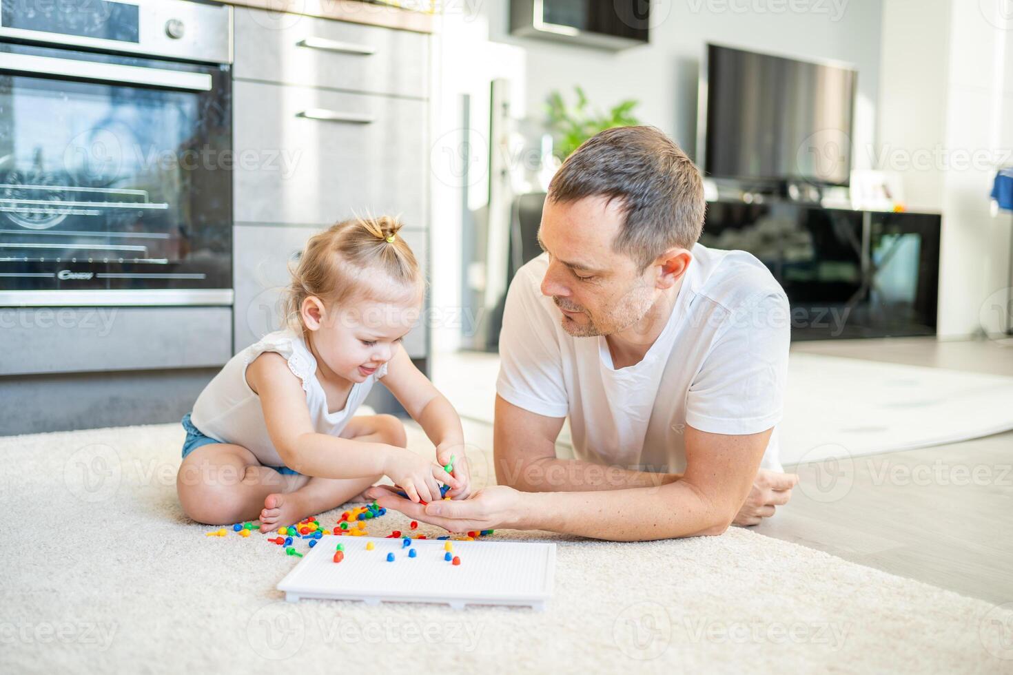 Cute little girl playing with mushroom nail mosaic. Father and baby playing together concept. Hobby and leisure time. photo