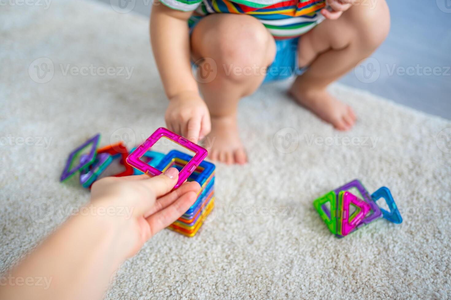 Little girl playing colorful magnet plastic blocks kit at home. The child playing educational games. Early childhood development. photo