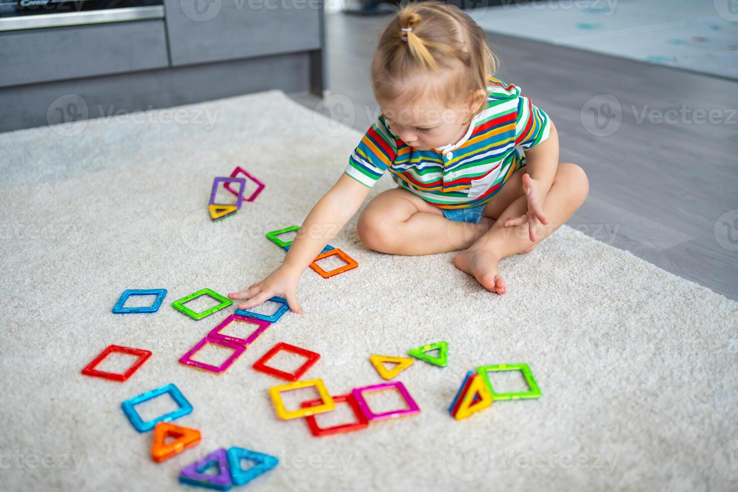 Little girl playing colorful magnet plastic blocks kit at home. The child playing educational games. Early childhood development. photo