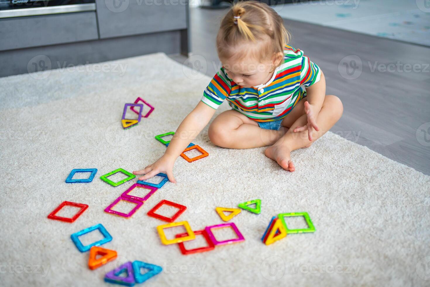 pequeño niña jugando vistoso imán el plastico bloques equipo a hogar. el niño jugando educativo juegos. temprano infancia desarrollo. foto