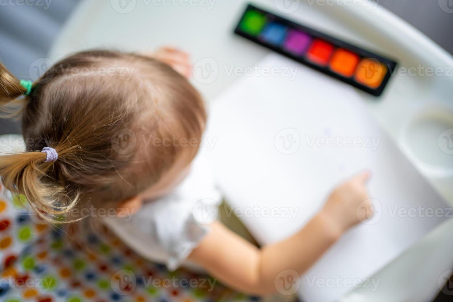 Cute little girl painting with fingers at home. Creative games for kids. Stay at home entertainment photo