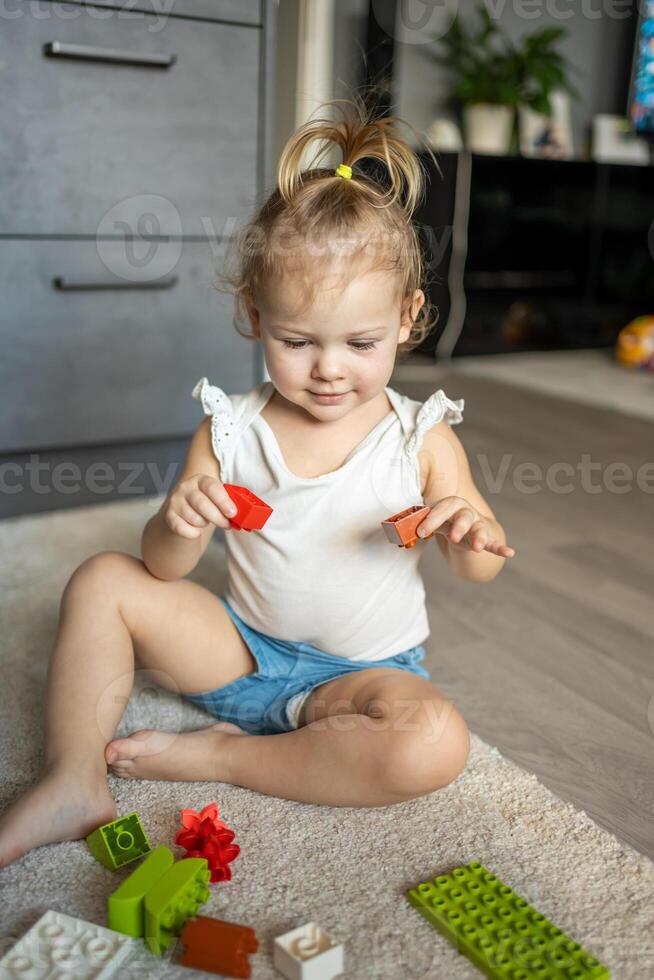 caucásico niño un pequeño niña es jugando en el constructor a hogar. educativo juguetes para niños. foto