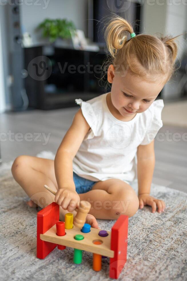 linda caucásico pequeño niña jugando en el piso a hogar con eco de madera juguetes el niño jugando educativo juegos. foto