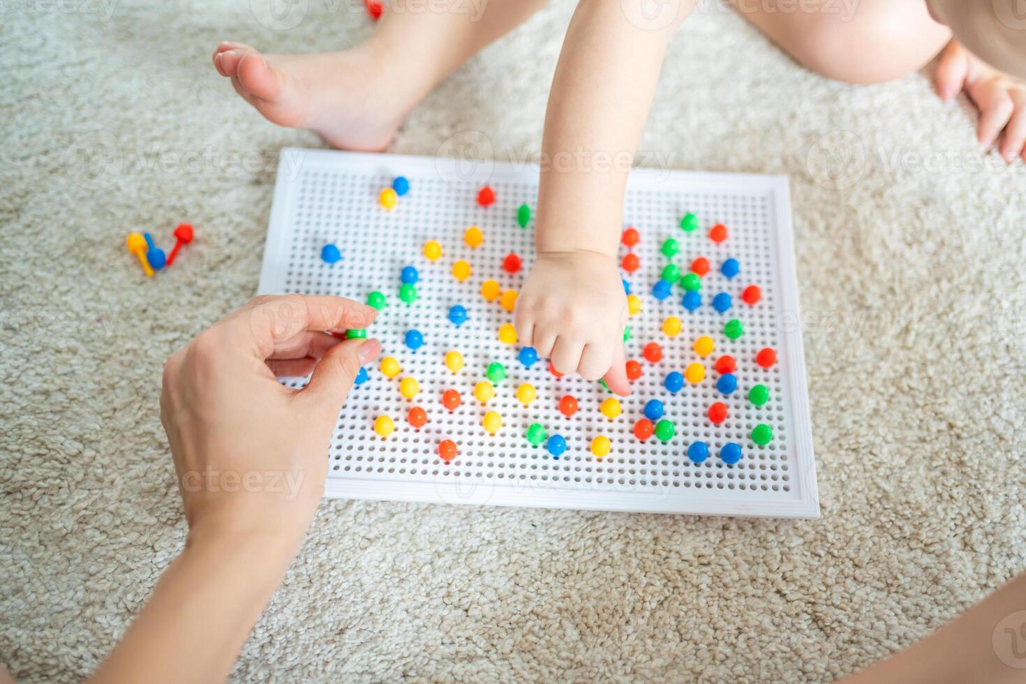 Cute little girl playing with mushroom nail mosaic. Father and baby playing together concept. Hobby and leisure time. photo