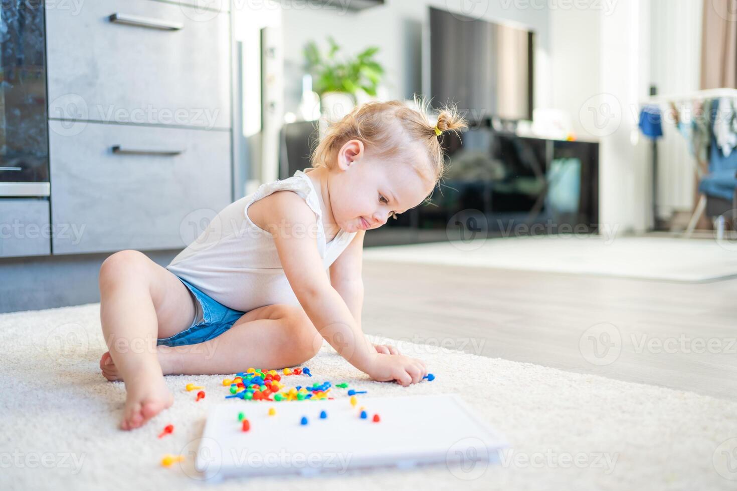 Pretty little girl playing with mushroom nail mosaic at home. Hobby and leisure time photo