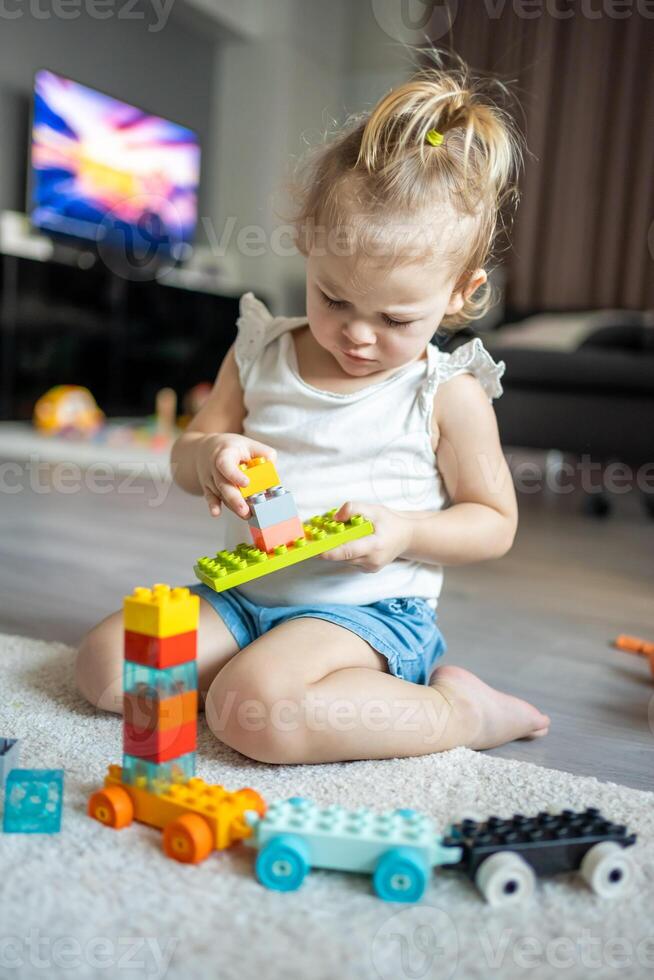 caucásico niño un pequeño niña es jugando en el constructor a hogar. educativo juguetes para niños. foto