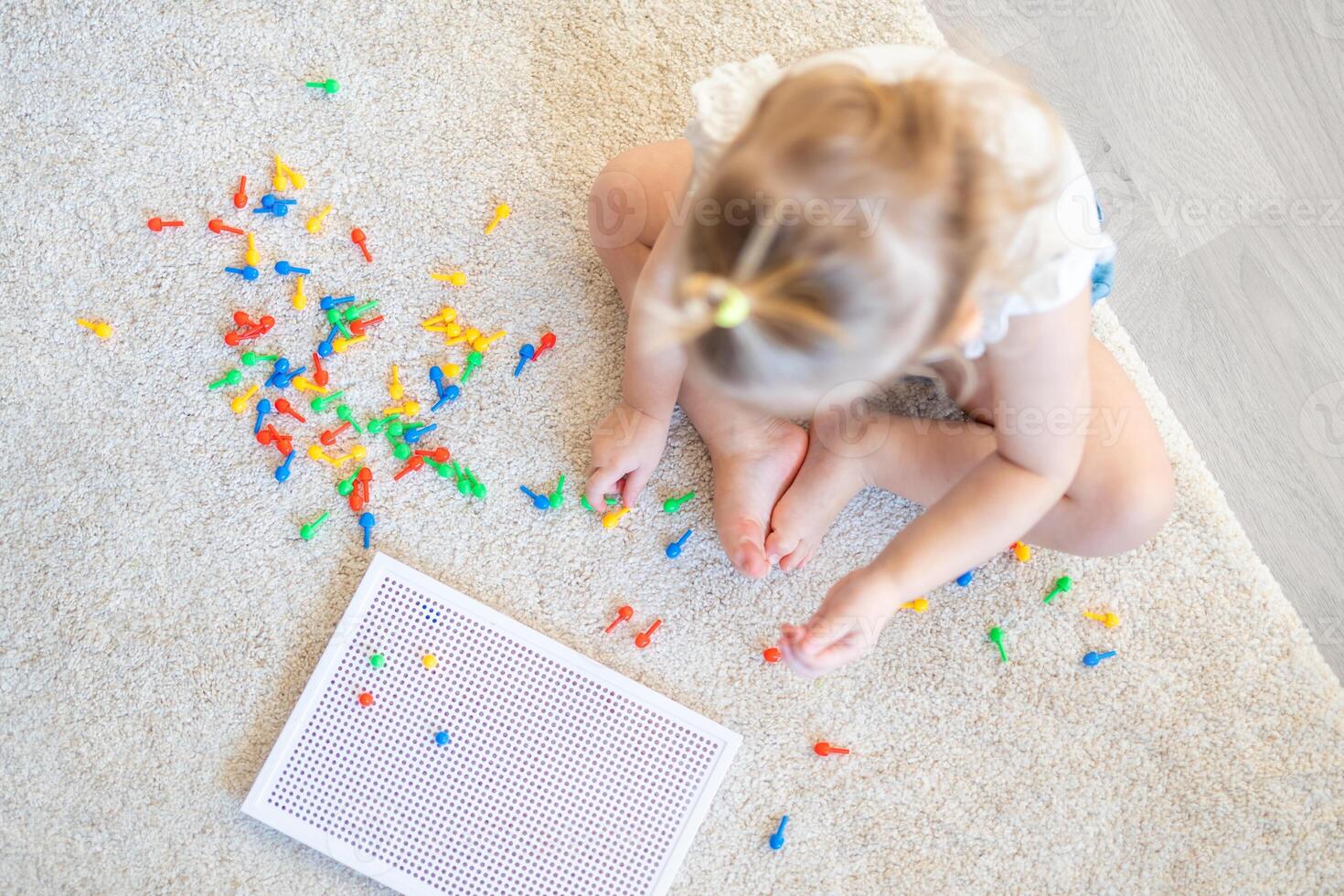 Pretty little girl playing with mushroom nail mosaic at home. Hobby and leisure time photo
