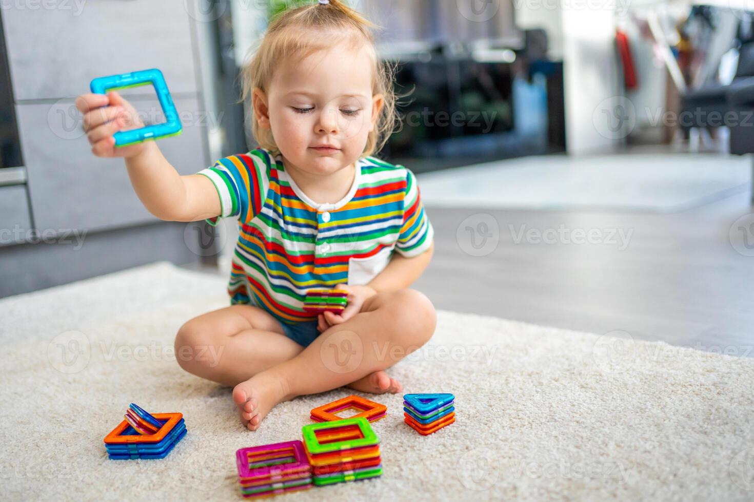 pequeño niña jugando vistoso imán el plastico bloques equipo a hogar. el niño jugando educativo juegos. temprano infancia desarrollo. foto