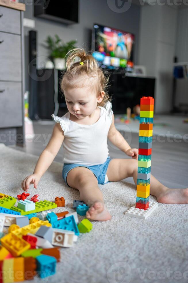 Caucasian child a little girl is playing in the constructor at home. Educational toys for children. photo