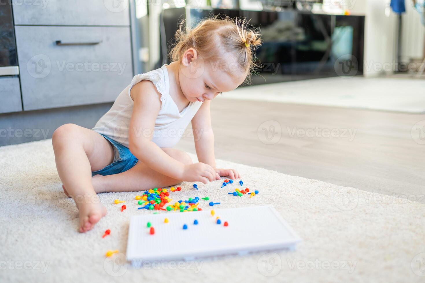Pretty little girl playing with mushroom nail mosaic at home. Hobby and leisure time photo