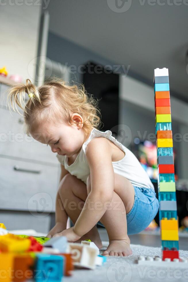 caucásico niño un pequeño niña es jugando en el constructor a hogar. educativo juguetes para niños. foto