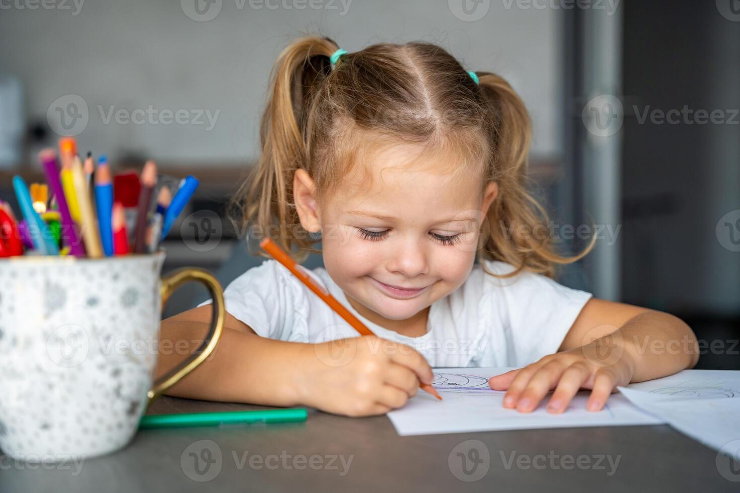 little girl draws with colored pencils in home. photo