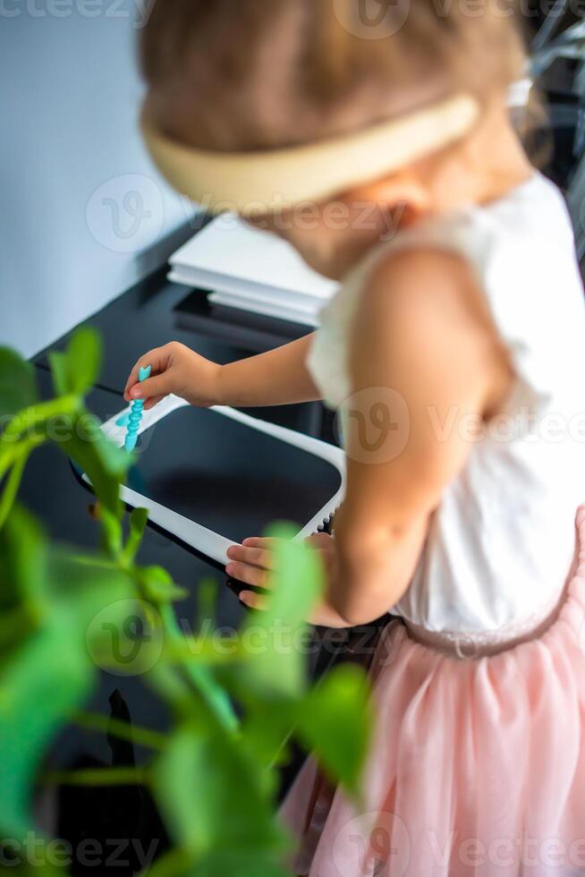 Little girl is drawing on Led tablet at home. View of child hand with painting scribble photo