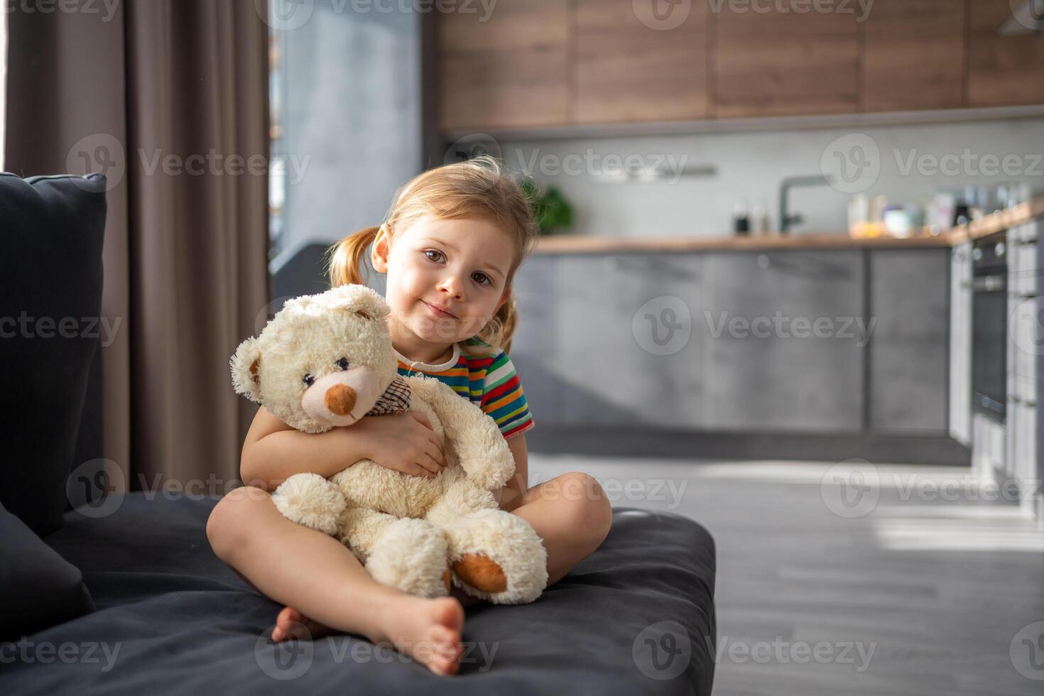 linda pequeño niña abrazando osito de peluche oso mientras sentado en sofá a hogar foto