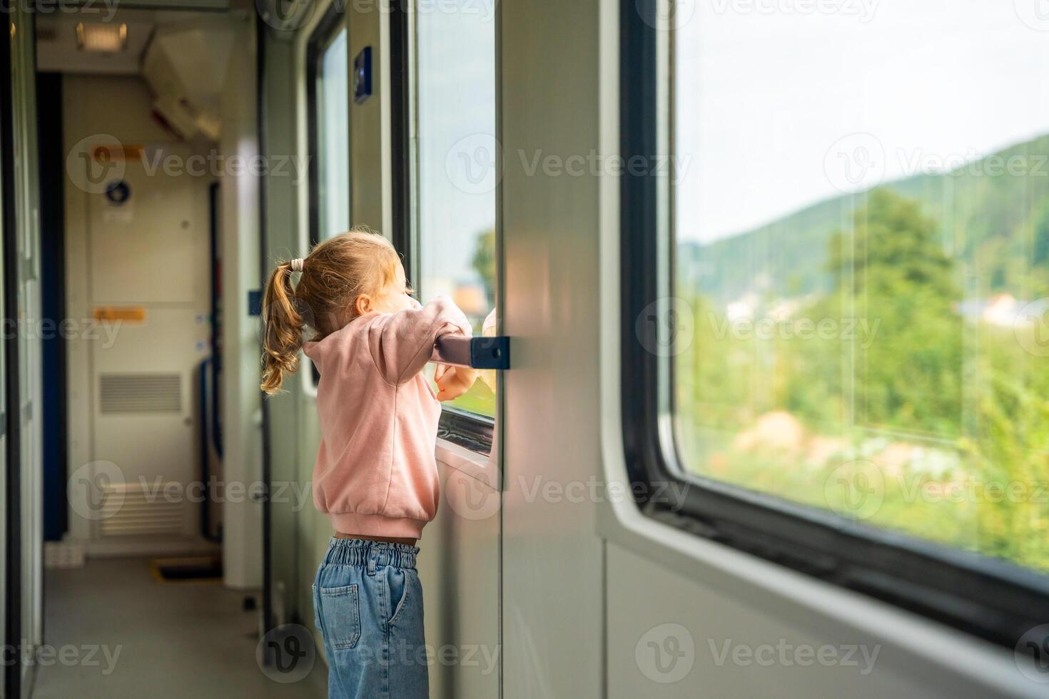 Cute little girl looking out train window outside, while it moving. Traveling by railway, Europe photo