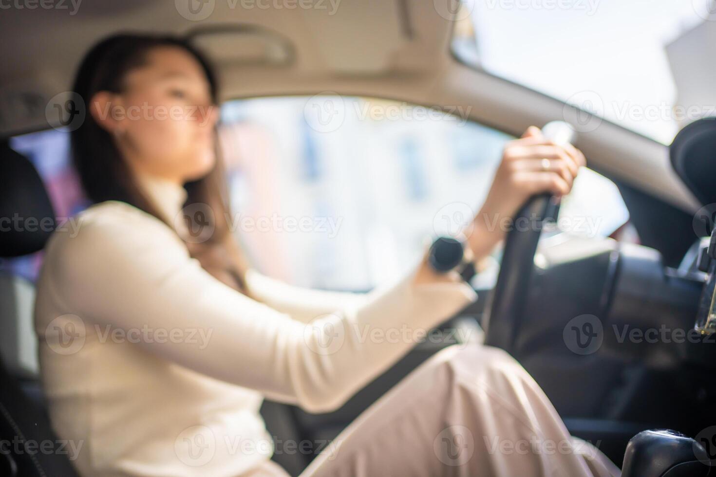 Blurred photo of happy woman driving a car and smiling. Cute young success happy brunette woman is driving a car. Portrait of happy female driver steering car.