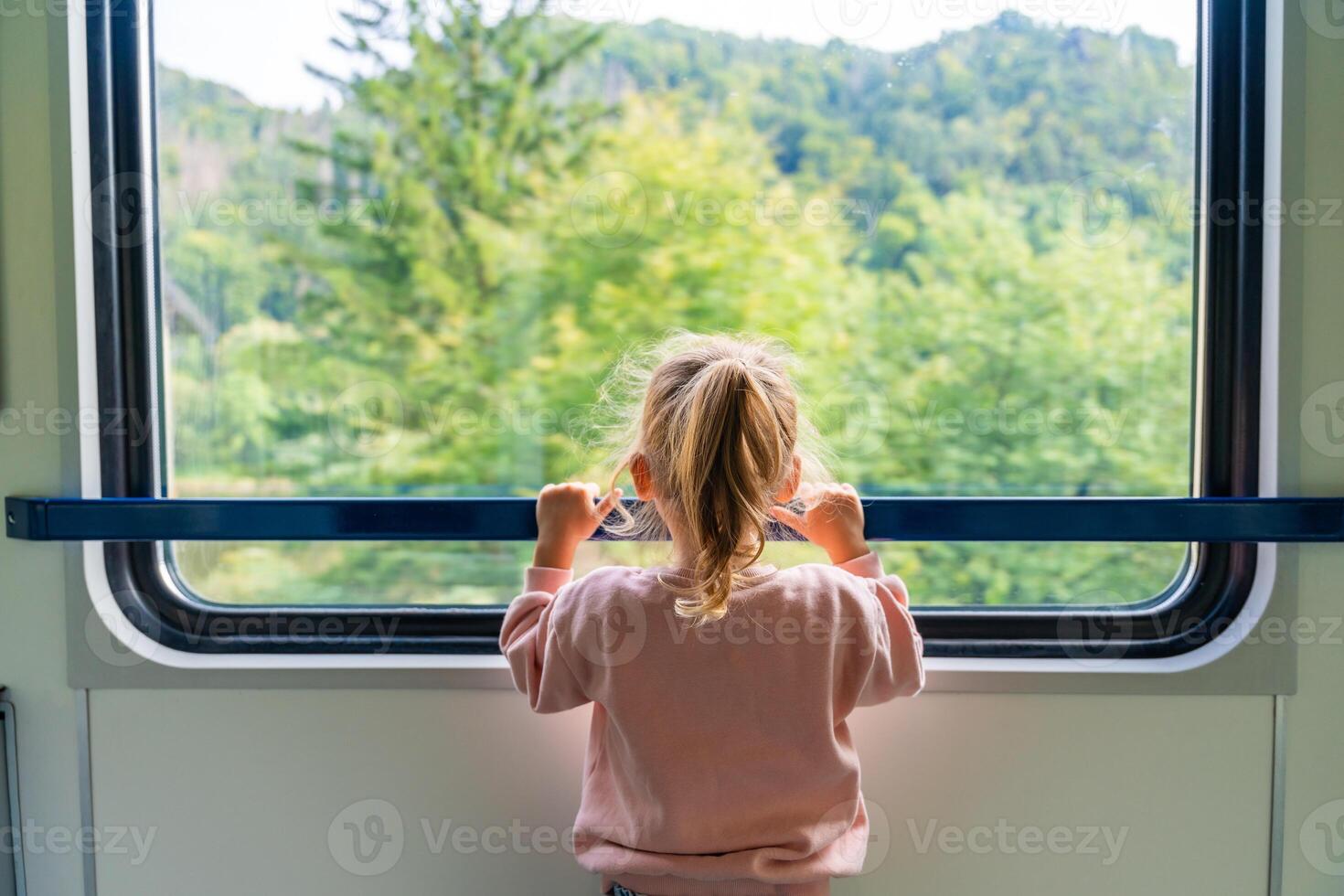 hermosa pequeño niña mirando fuera tren ventana afuera, mientras eso Moviente. de viaje por ferrocarril en Europa foto