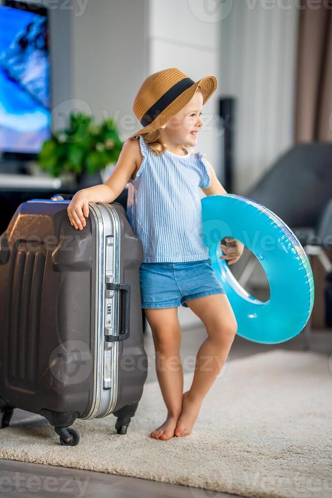 Little girl with suitcase baggage luggage and inflatable life buoy ready to go for traveling on vacation photo