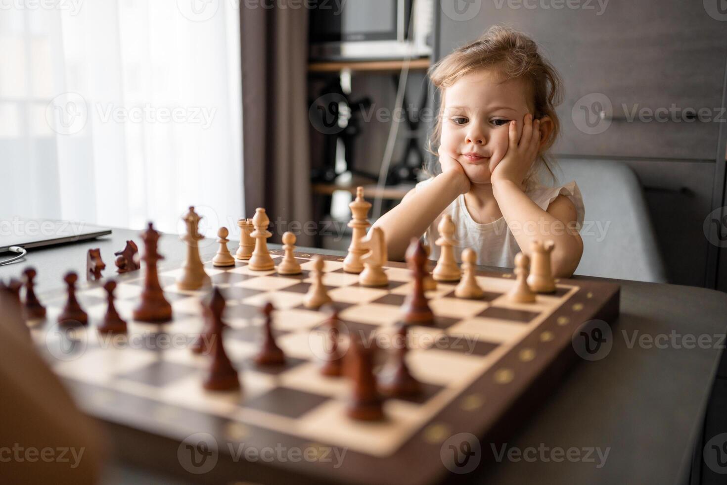 Little girl playing chess with her father at the table in home kitchen. The concept early childhood development and education. Family leisure, communication and recreation. photo