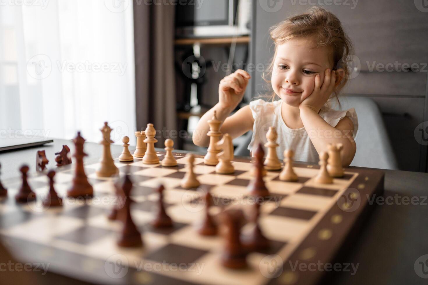 pequeño niña jugando ajedrez a el mesa en hogar cocina. el concepto temprano infancia desarrollo y educación. familia ocio, comunicación y recreación. foto