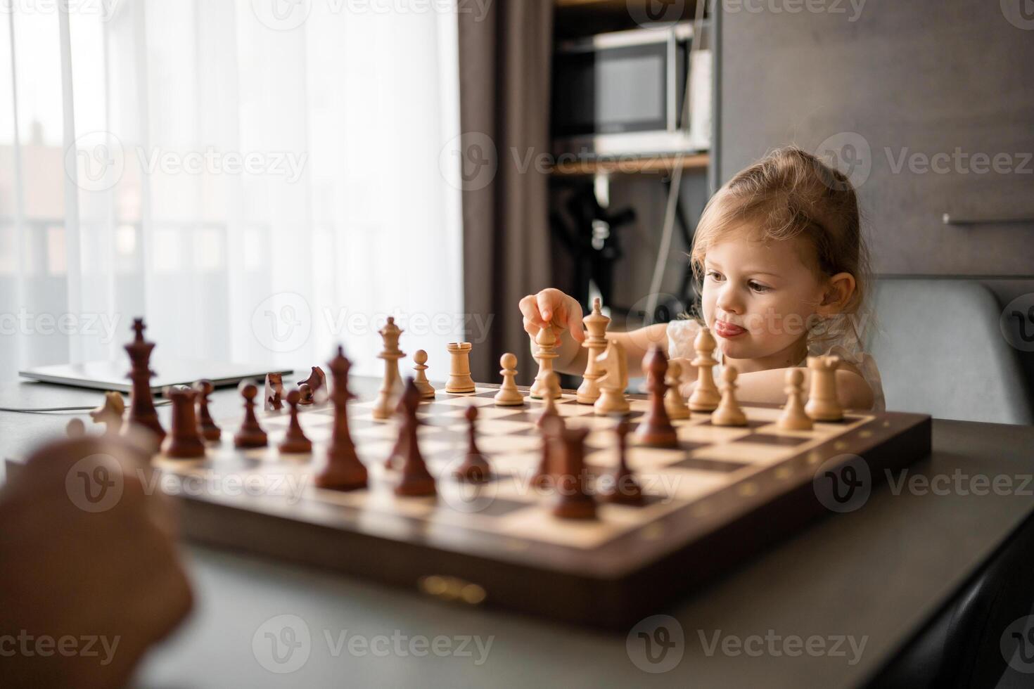 pequeño niña jugando ajedrez con su padre a el mesa en hogar cocina. el concepto temprano infancia desarrollo y educación. familia ocio, comunicación y recreación. foto