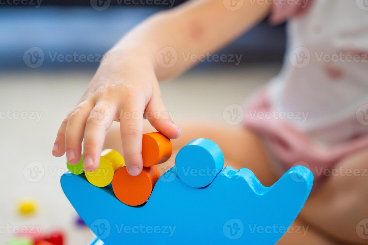 Little girl playing with wooden balancing toy on the floor in home living room. Focus on balancer photo