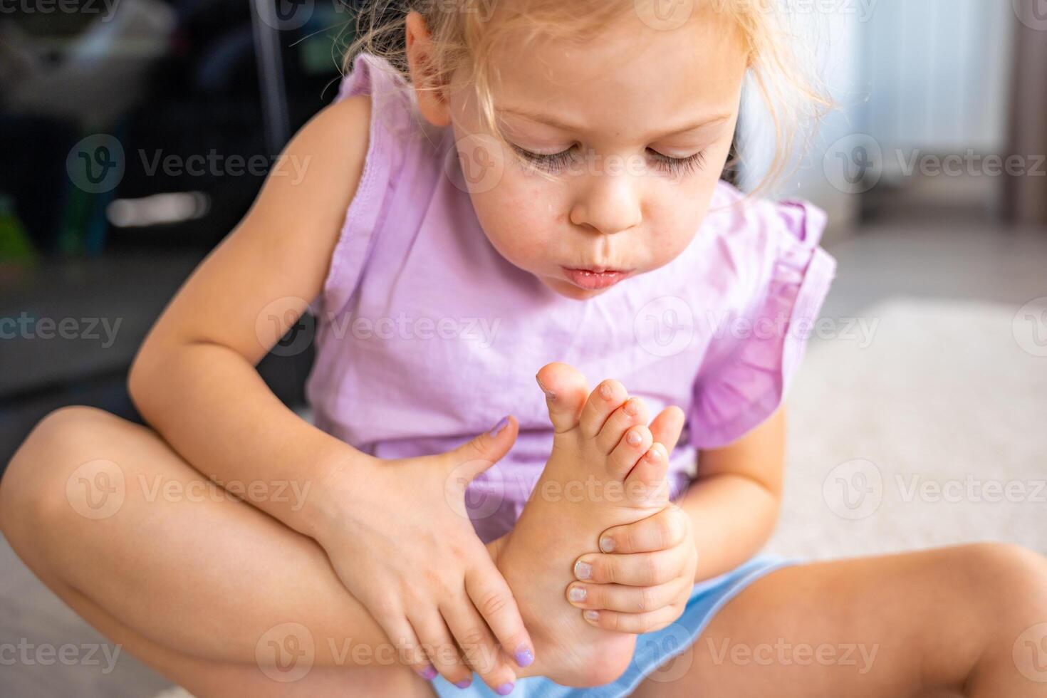 pequeño niña haciendo pedicure y pintura uñas con vistoso rosa, azul y púrpura uña polaco a hogar. niño niña soplo en tu uñas a seco el polaco. foto