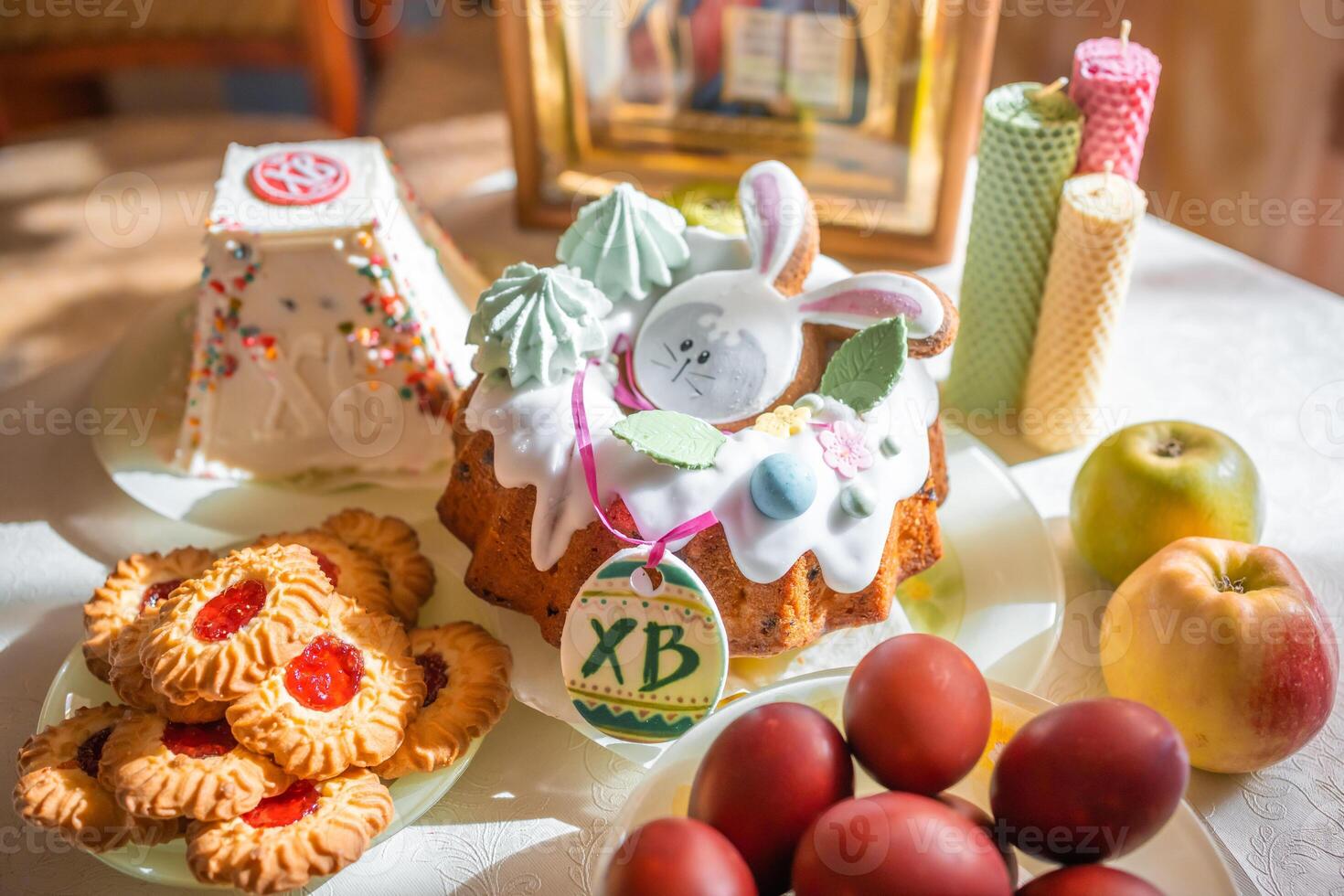 Easter cake with painted eggs, apples and cookies on table in home kitchen. Church icons and candle on background. Orthodox religion theme. High quality photo