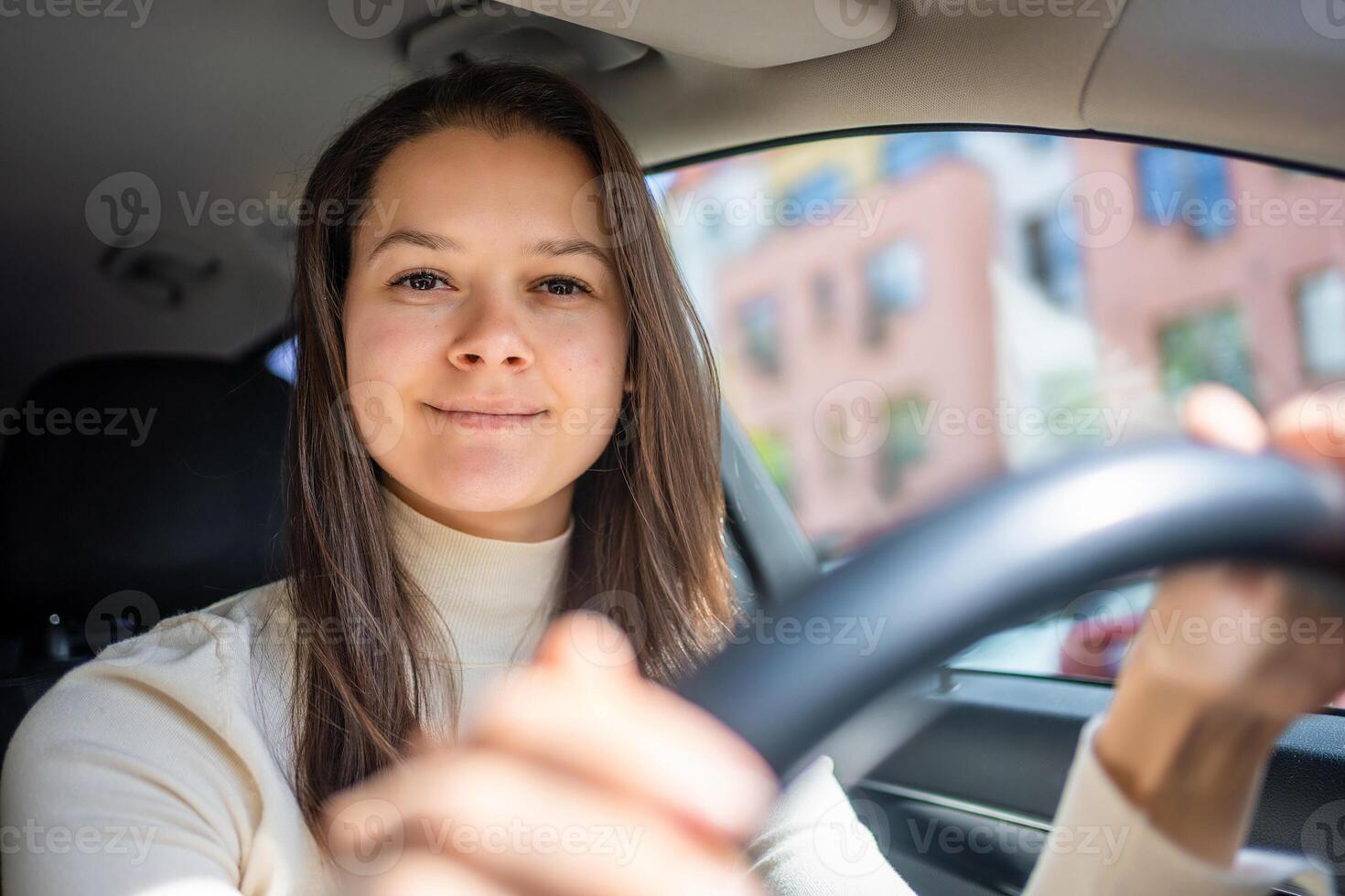 Happy woman driving a car and smiling. Cute young success happy brunette woman is driving a car. Portrait of happy female driver steering car. photo