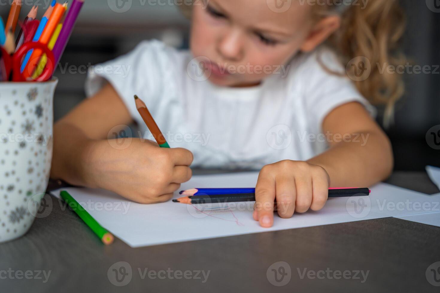 little girl draws with colored pencils in home. photo