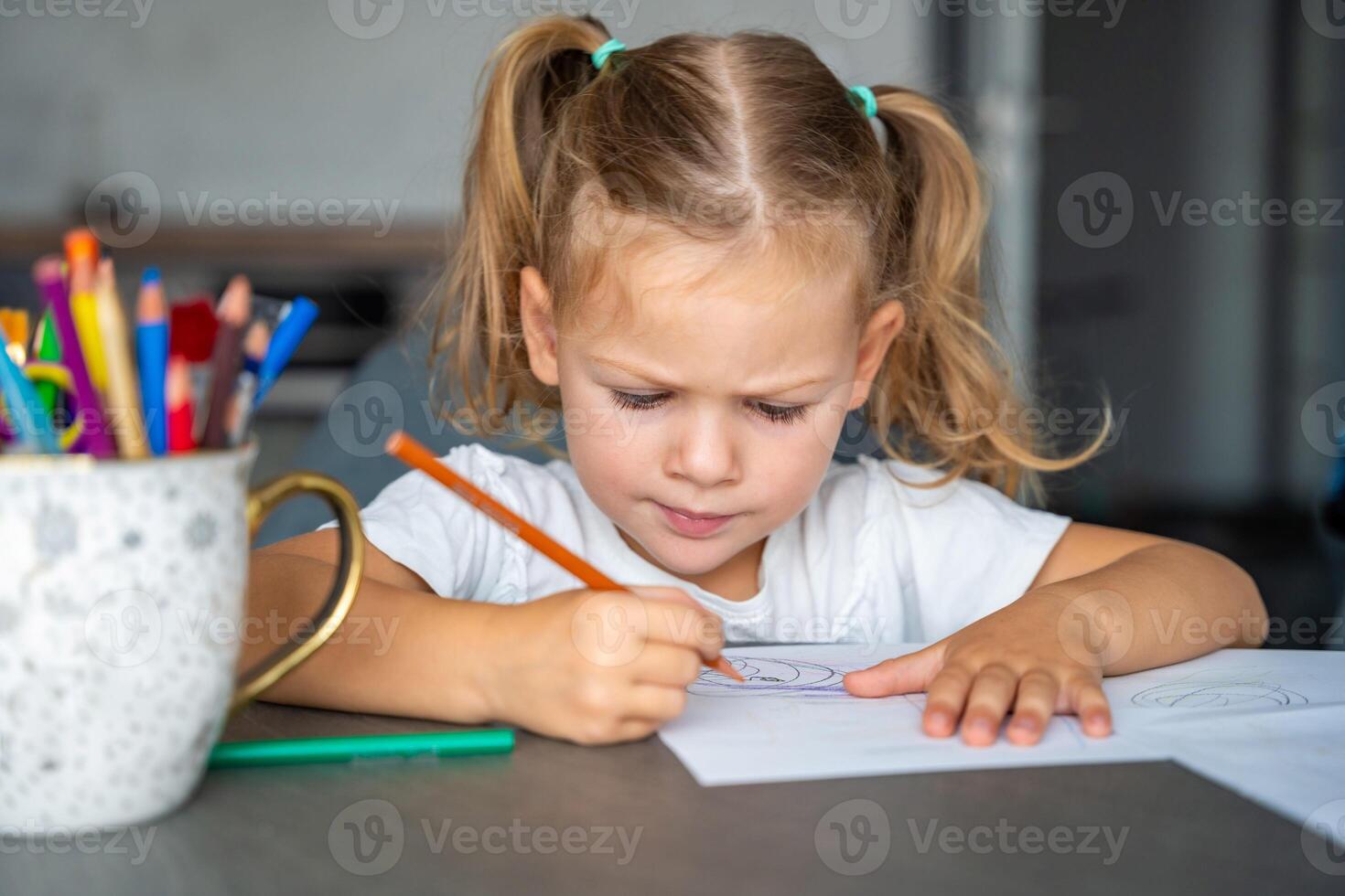little girl draws with colored pencils in home. photo