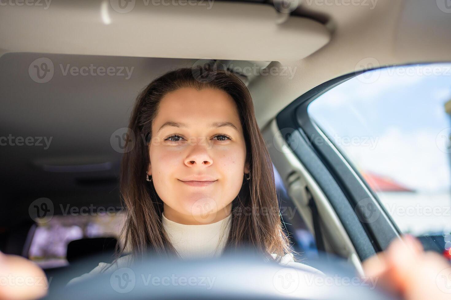 Happy woman driving a car and smiling. Cute young success happy brunette woman is driving a car. Portrait of happy female driver steering car. photo