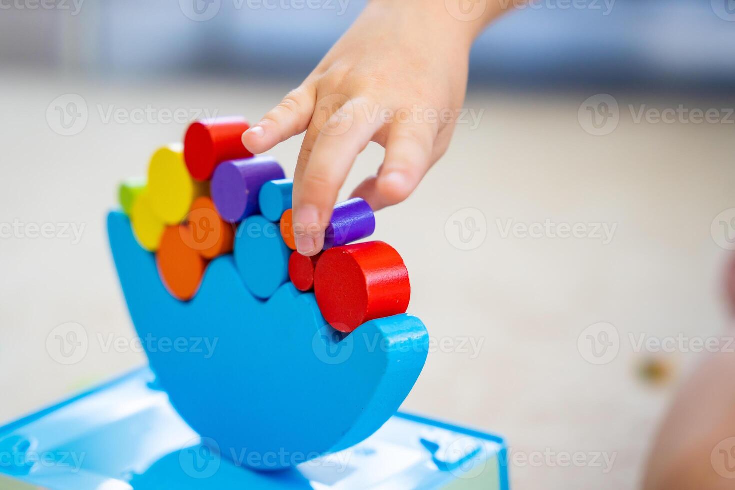 Little girl playing with wooden balancing toy on the floor in home living room. Focus on balancer photo