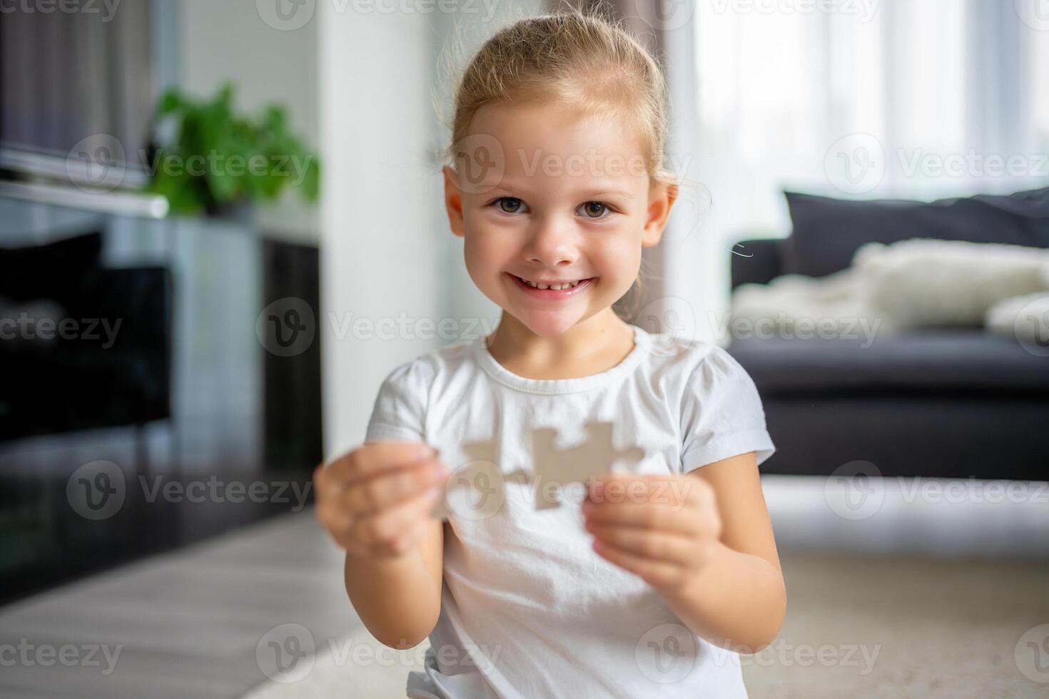 Portrait of Little blonde girl sits at home on the carpet and collects puzzles photo