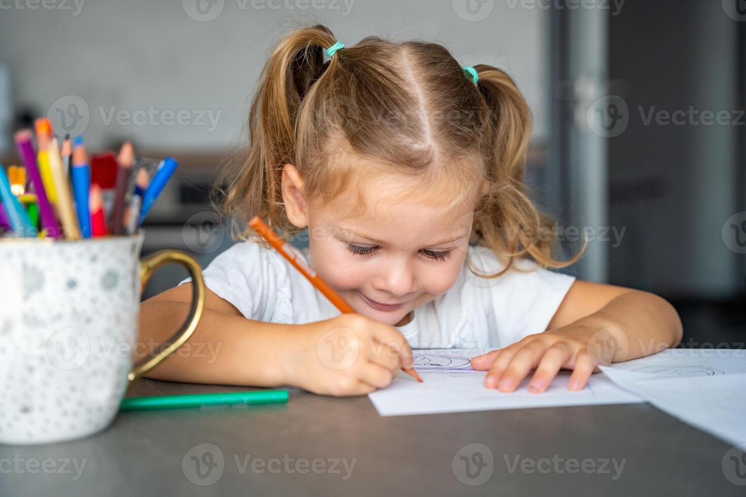 little girl draws with colored pencils in home. photo