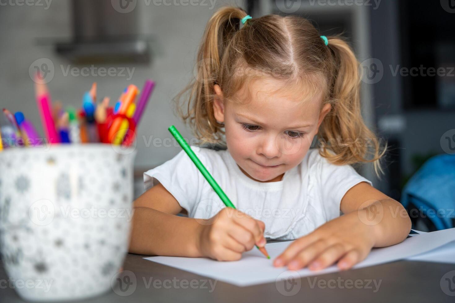 little girl draws with colored pencils in home. photo