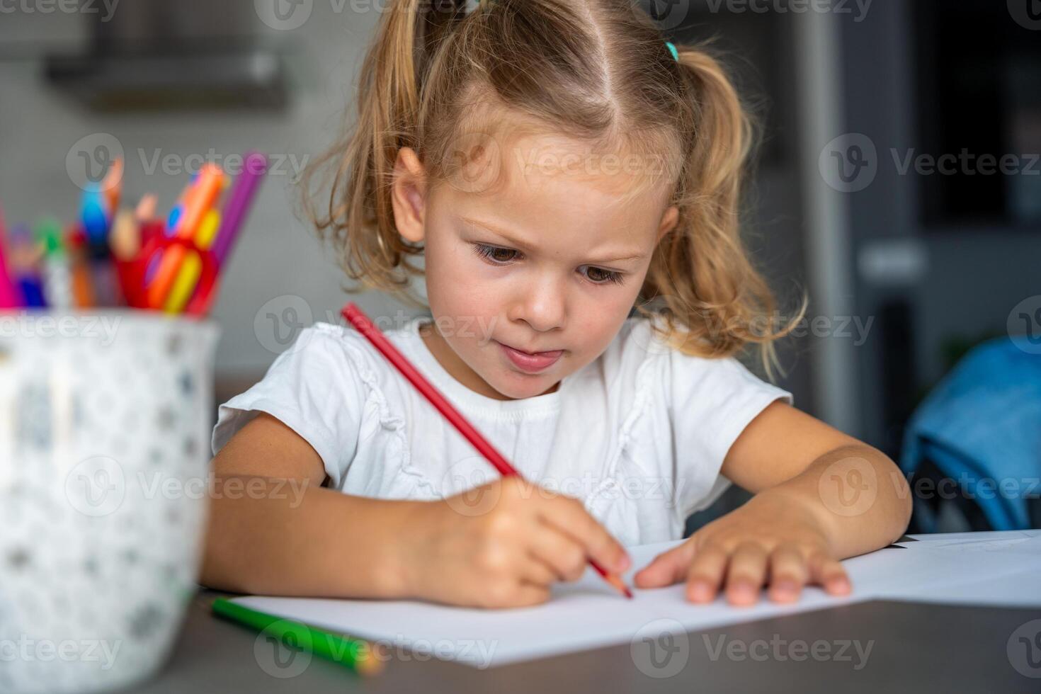 little girl draws with colored pencils in home. photo