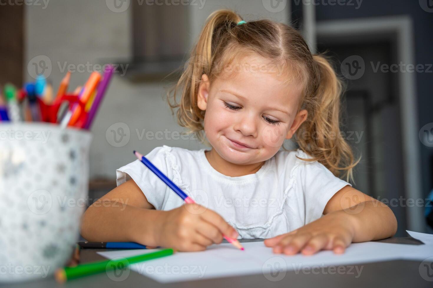 little girl draws with colored pencils in home. photo