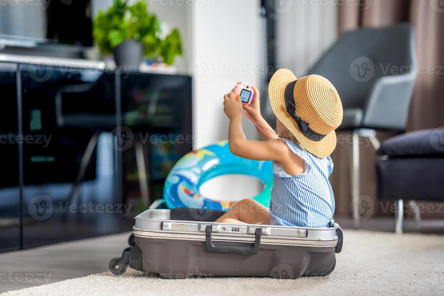 Little girl with suitcase baggage luggage and inflatable life buoy playing with toy camera and ready to go for traveling on vacation photo